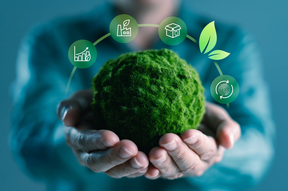 Hands holding a green moss globe with sustainability icons